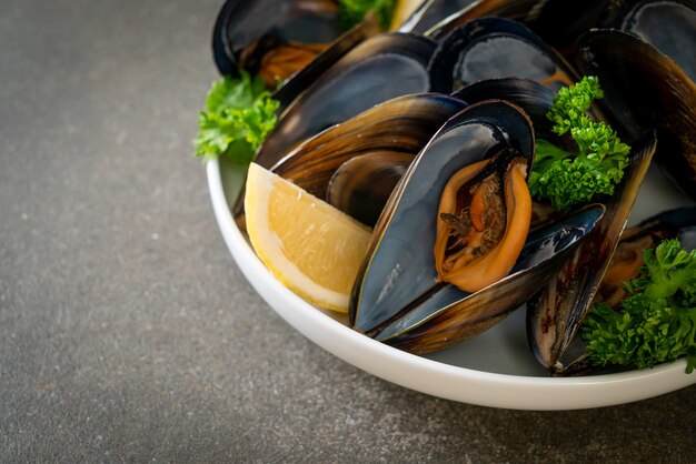 mejillones frescos con hierbas en un bol con limón