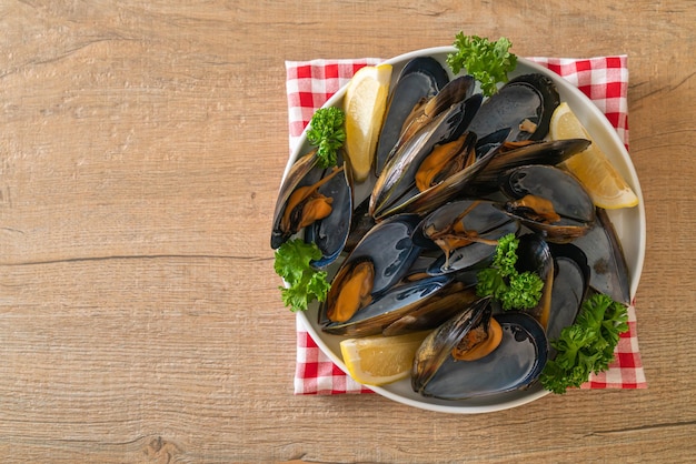 mejillones frescos con hierbas en un bol con limón