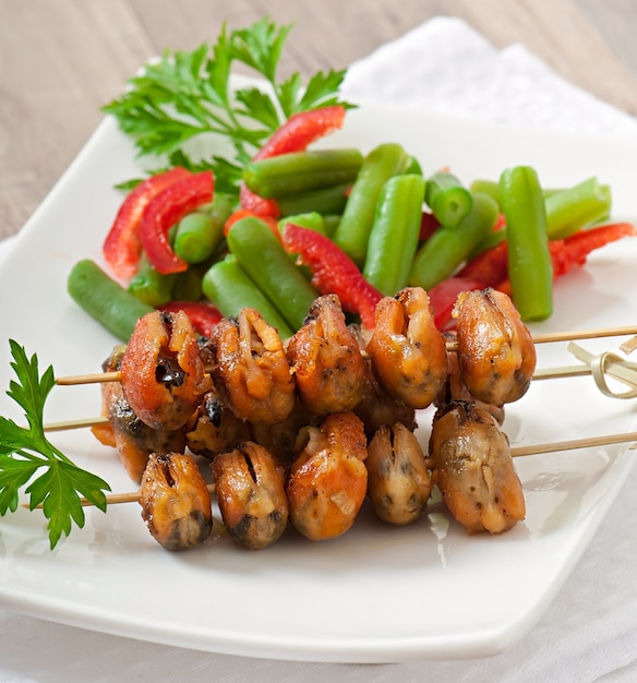 Foto mejillones fritos con cebolla en brochetas c guarnición de judías verdes y pimentón