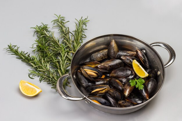 Mejillones de Marisco en sartén. Romero y limón en mesa. Mariscos mariscos. Endecha plana