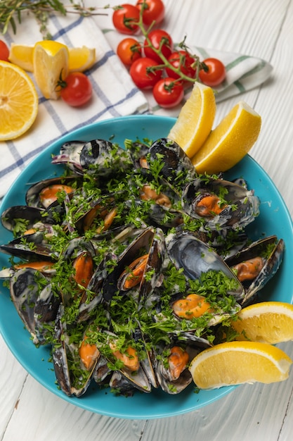 Mejillones en un plato con limón sobre una mesa blanca