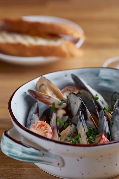 Mejillones con salsa en plato y pan a la plancha sobre mesa de madera de cerca. concepto de restaurante