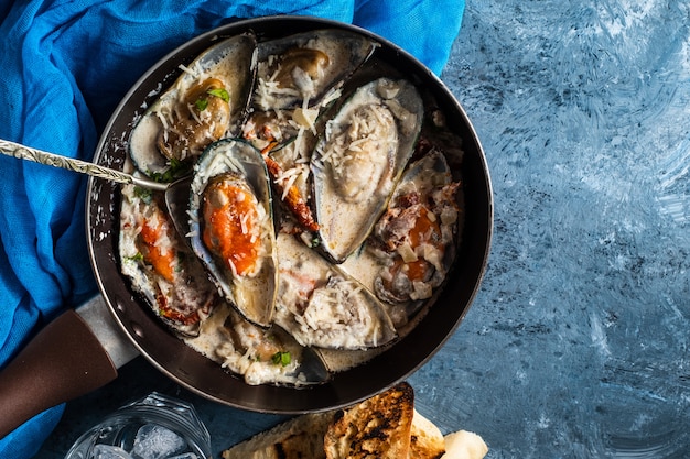 Mejillones con salsa de queso azul y baguette de ajo.