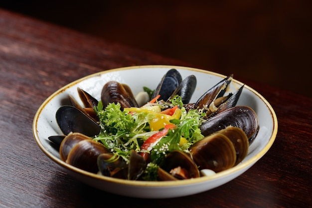 Mejillones con semillas de sésamo en un plato sobre un fondo de madera