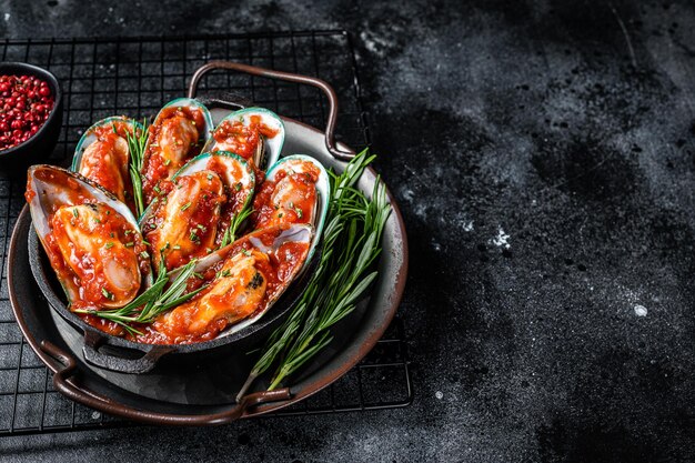 Mejillones verdes al vapor con salsa marinara Fondo negro Vista superior Espacio de copia