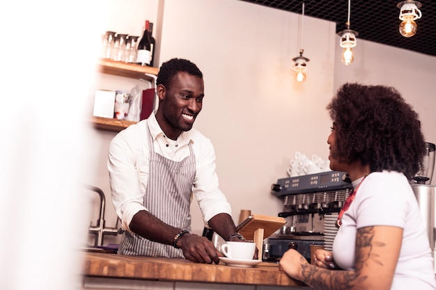 El mejor café. Buen hombre alegre sonriendo mientras sirve café al cliente