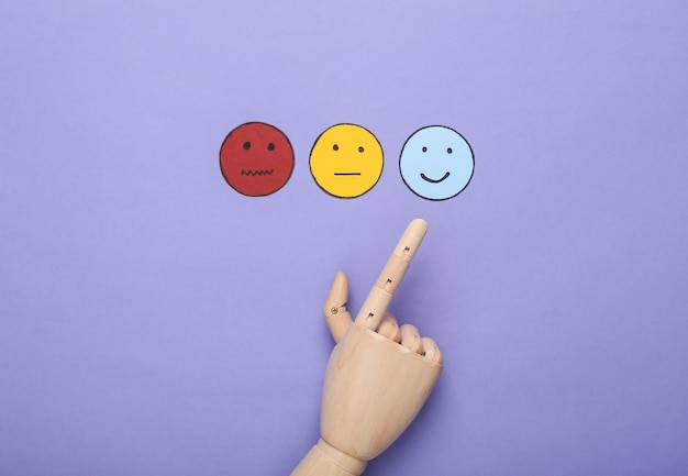 Mejor concepto de encuesta de satisfacción del cliente de servicio La mano elige el icono de la cara feliz icono de papel de cara neutral y triste en fondo violeta Vista superior
