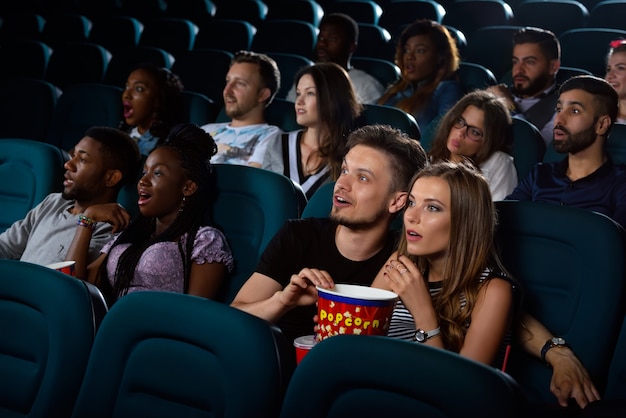 Mejor entretenimiento para citas. Retrato de una joven pareja sorprendida disfrutando de una película en el cine en su cita nocturna