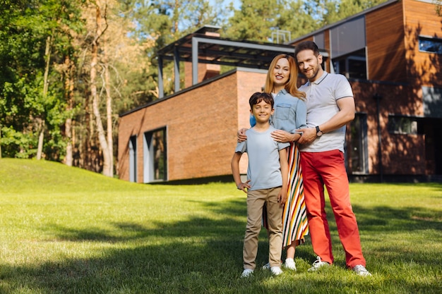 Mejor familia. Padres amorosos felices sonriendo y de pie con su hijo