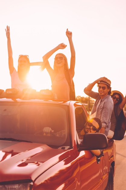 Foto el mejor viaje por carretera de todos los tiempos. grupo de jóvenes alegres disfrutando de su viaje por carretera mientras están sentados juntos en una camioneta