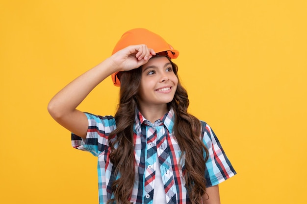 Mejore su infancia, el futuro ingeniero, el día de los trabajadores, haciendo reparaciones, una adolescente alegre con casco, un niño, use un casco para la protección del edificio y la seguridad, la educación de los niños en el sitio de construcción.