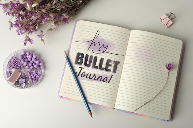 Mejore su productividad Cuaderno con palabras Papelería My Bullet Journal y flores en una mesa blanca plana