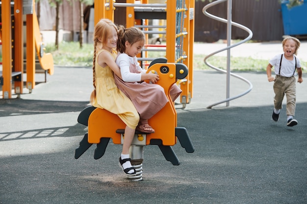 Mejores amigas jugando con un caballo de primavera en un parque infantil