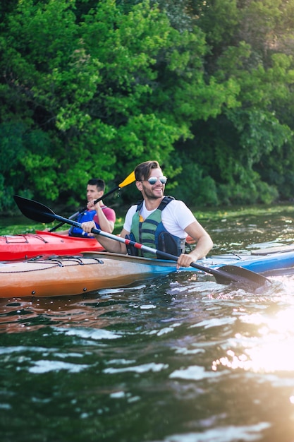 Mejores amigos felices divirtiéndose en kayaks. Kayak en el río. Dos amigos en un barco navegando por el río.