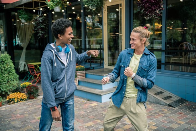 Mejores amigos. Hombres felices encantados mirándose mientras están parados juntos cerca de la casa