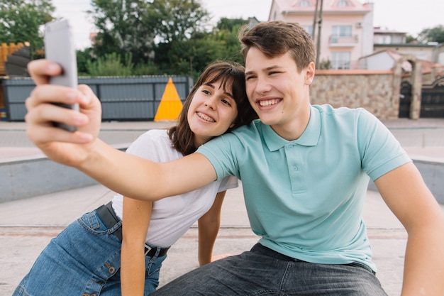 Los mejores amigos que toman selfie al aire libre con luz de fondo - concepto de amistad feliz con adolescente