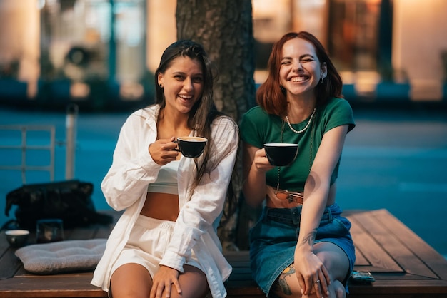 Mejores amigos sentados en el banco del parque tomando café