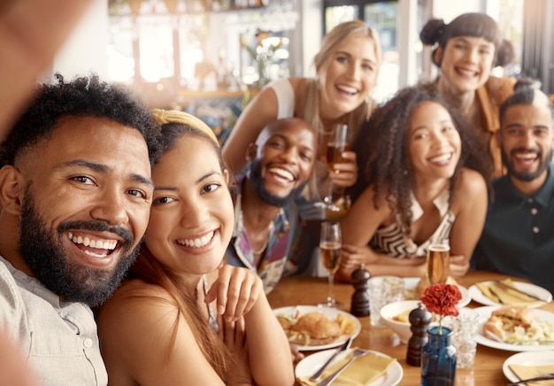 Las mejores personas para tener alrededor. Foto de un grupo de jóvenes amigos tomándose selfies juntos en un restaurante.