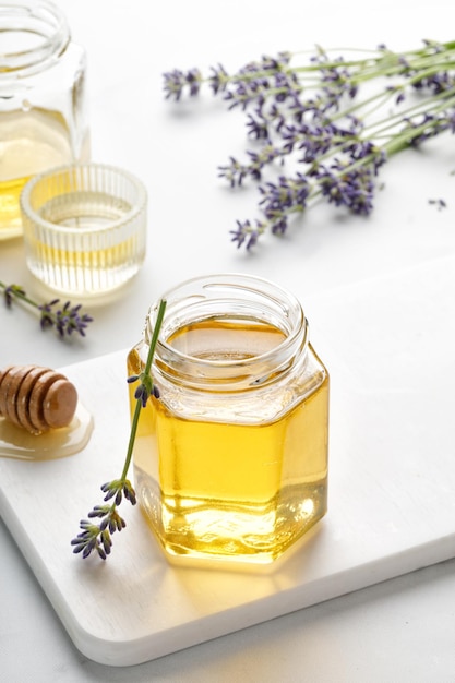 Mel de lavanda em frasco de vidro aberto com flores de lavanda em um quadro branco e fundo