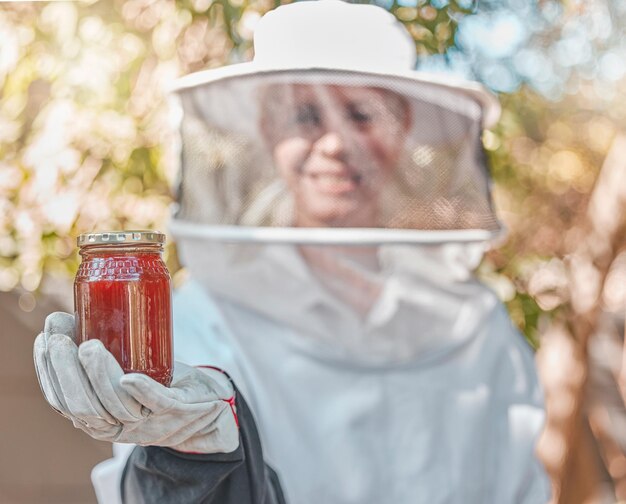 Mel de mão e jarra com uma apicultor trabalhando no campo na produção de um produto natural Agricultura agrícola e sustentabilidade com uma agricultora segurando um pote de mel ao ar livre