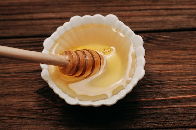 Mel de tília fresco líquido em um prato com uma colher de mel de madeira
