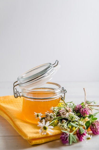 Mel floral fresco no frasco e flores em um fundo branco com um espaço de cópia