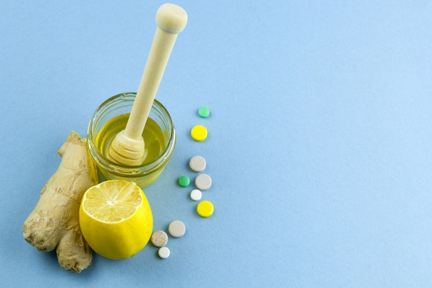 Mel, limão, gengibre e frio pílulas fundo azul, lugar para texto