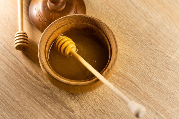 Mel pingando da concha de mel na tigela de madeira. fechar-se. orgânico saudável. mel grosso mergulhando da colher de mel de madeira, closeup