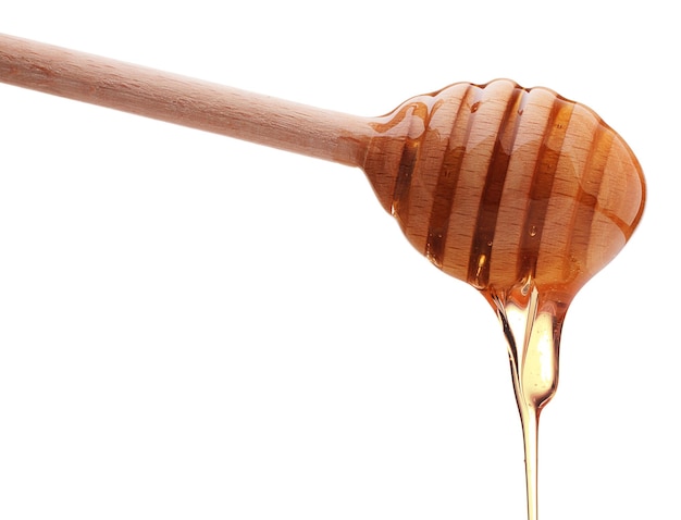 Mel pingando de uma concha de mel de madeira isolada em um recorte de fundo branco