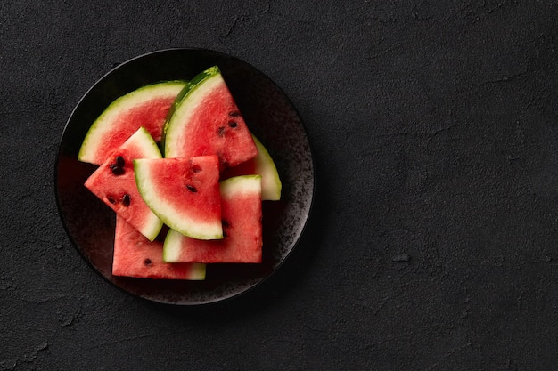 Melancia plana com vista superior em fundo preto Frutas fatiadas no prato