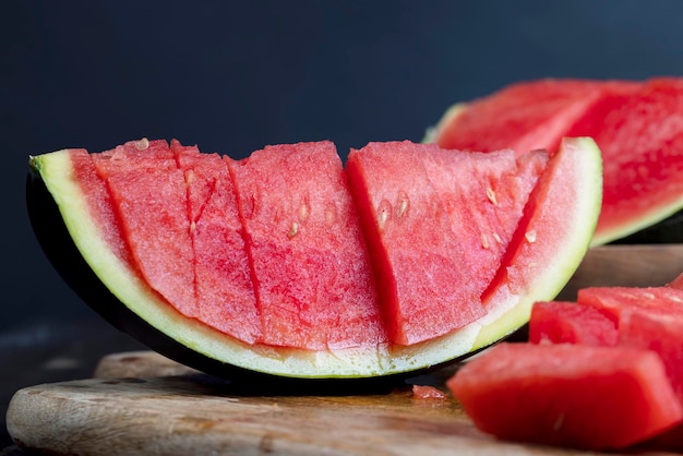 Melancia vermelha madura cortada em pedaços com fatias de sementes pretas de melancia vermelha doce