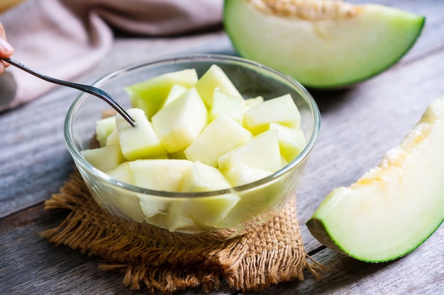 Melão verde doce fresco em tigela de vidro no fundo da mesa de madeira. Conceito de frutas. fechar-se