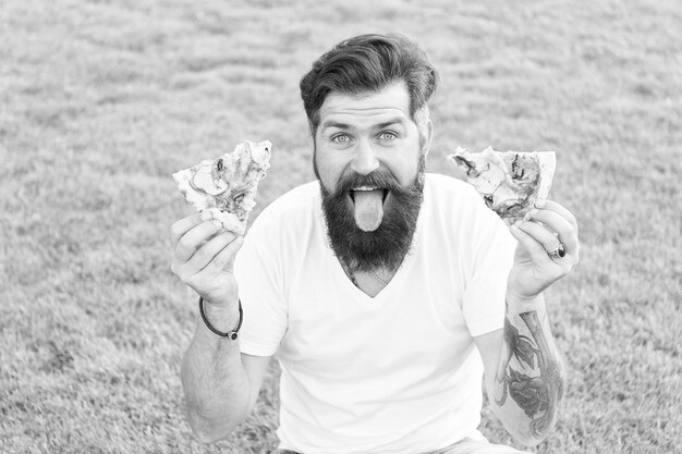 Foto melhor comida de sempre hipster barbudo comendo pizza deliciosa homem ganancioso com fome segura pizza nas duas mãos cara alegre come pizza conceito de piquenique de verão homem caucasiano amando comida tradicional italiana