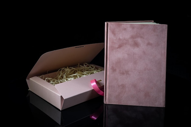 Melhor presente para homens Conceito de presente de homem Caderno rosa com caixa de presente rosa em fundo preto Copie o texto do espaço Dia dos namorados aniversário de casamento e conceito de presente de ocasião especial Copie o espaço para texto