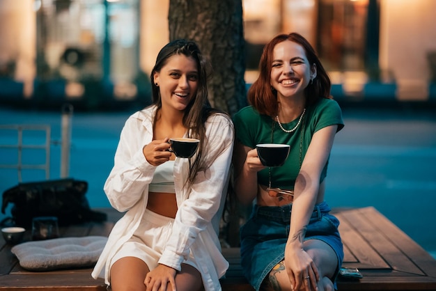 Melhores amigos sentados no banco do parque tomando café