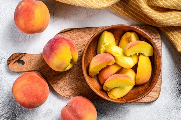 Melocotones en rodajas, fruta orgánica en un cuenco de madera.