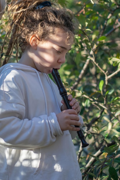 Melodías mágicas Un niño con dreadlocks tocando la flauta en el parque encantado