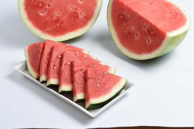 melón de agua dulce en rodajas en plato blanco sobre fondo blanco