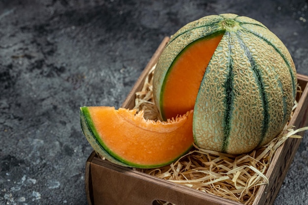 Foto melón cantalupo entero y rebanada de melón japonés melón naranja con semillas en el lugar de fondo oscuro para la vista superior del texto