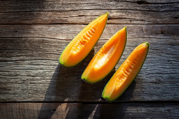 Foto melón dulce fresco cortado en el tablero de madera. textura de color naranja vista superior .