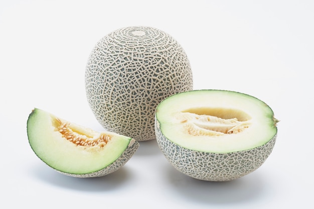 Melón fresco del cantalupo de Hami con las rebanadas aisladas en el fondo blanco.