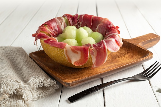 Melón con jamón secado al aire, servido en melón a la mitad relleno de jamón serrano y bolitas de melón. copia espacio