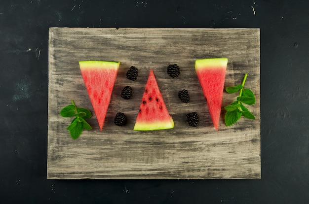 Foto melón, sandía, moras y menta en una mesa de madera