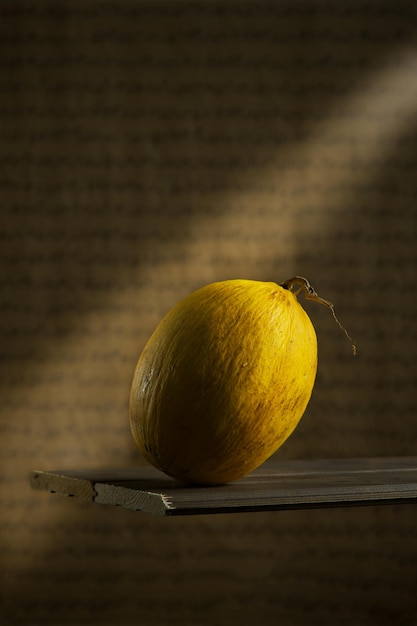 Melone auf dunklem Hintergrund, gelbe Früchte, Sonnenstrahl, auf einem Holztisch, Fotos für eine Zeitschrift oder ein Menü