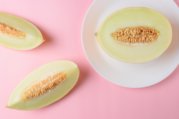 Melone auf pastellrosa Oberfläche geschnitten.