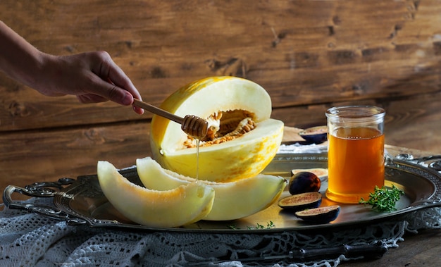 Foto melone mit honig, feigen, auf einem rustikalen holztisch