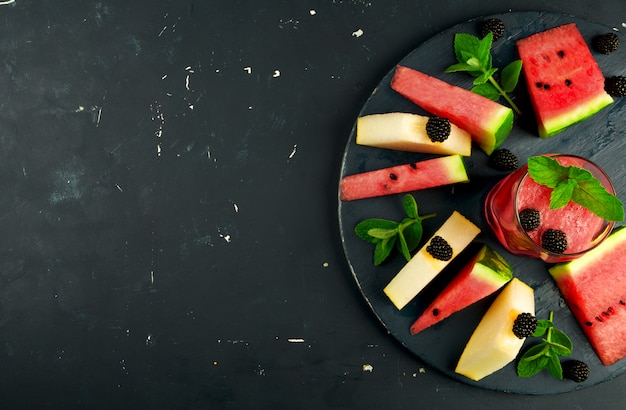 Melone, Wassermelone, Brombeeren und Minze auf einem Holztisch