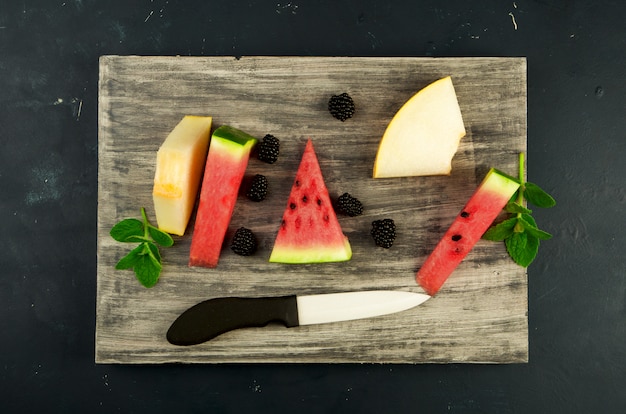 Melone, Wassermelone, Brombeeren und Minze auf einem Holztisch