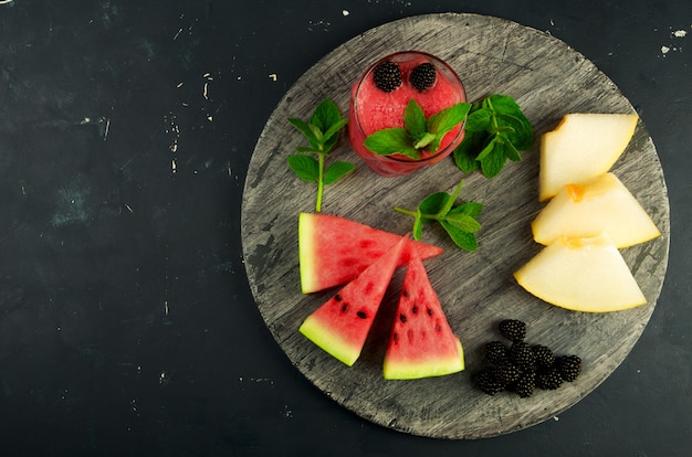 Melone, Wassermelone, Brombeeren und Minze auf einem Holztisch