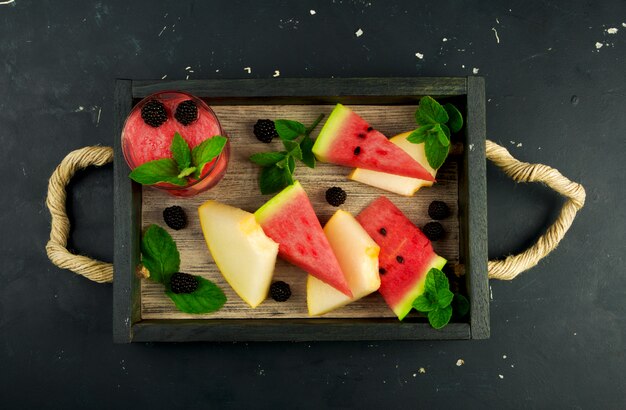 Melone, Wassermelone, Brombeeren und Minze auf einem Tablett